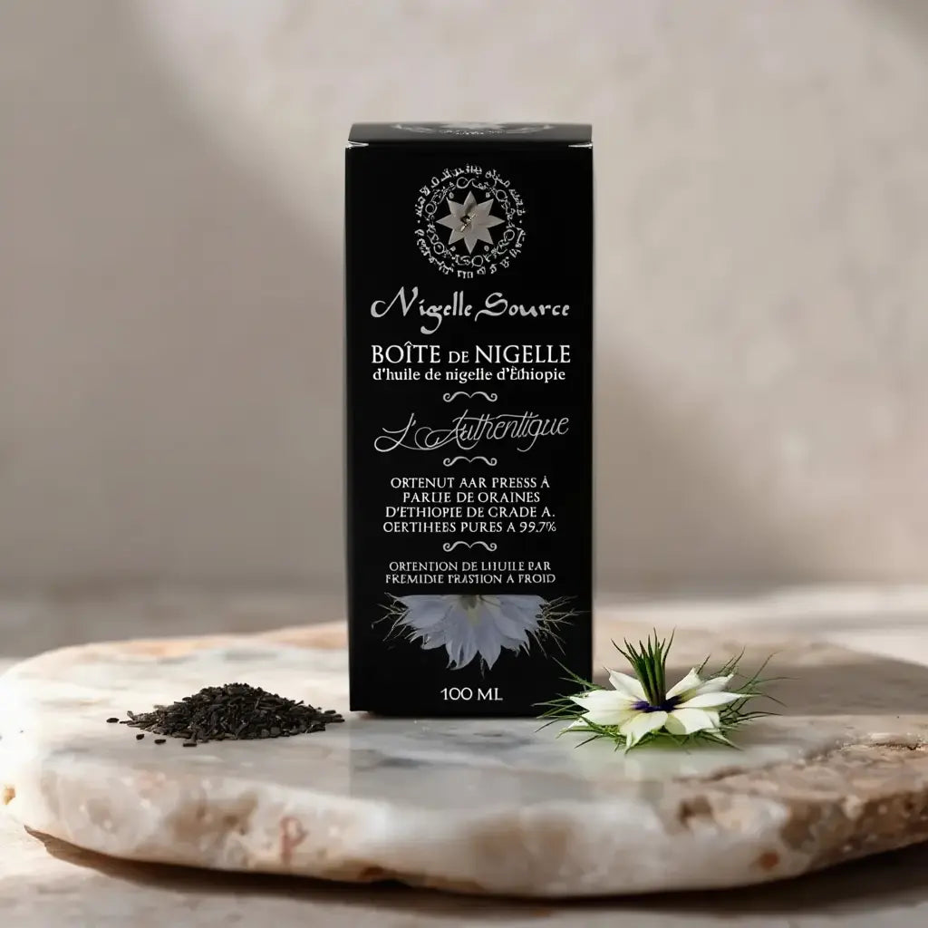 Boîte noire d’huile de nigelle éthiopienne Nigelle Source sur pierre, lotus blanc et pavot de nigelle à côté, texte élégant sur l’emballage 100 ml