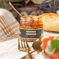 Pot ouvert de harissa prestige Tava Hada Pilpelta avec une cuillère, du pain et des couverts